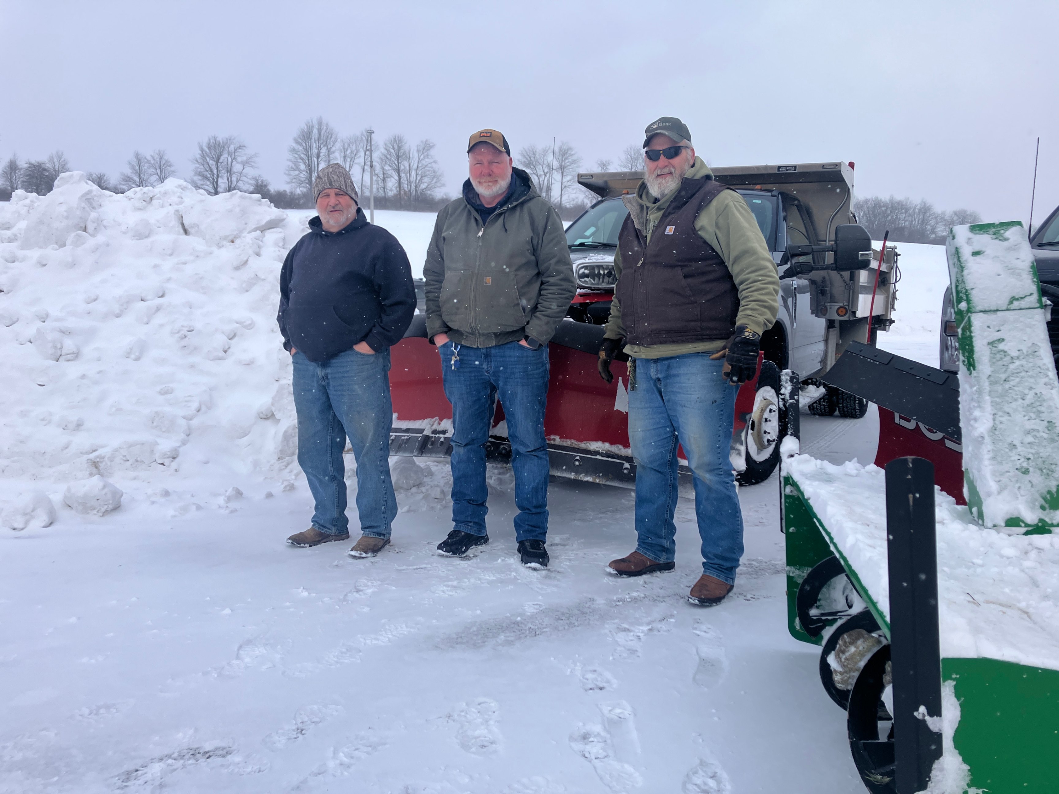 Don Pangallo, Gary Steele, and Dave Shiock pose for a photo in front of their snow clearing equipment.